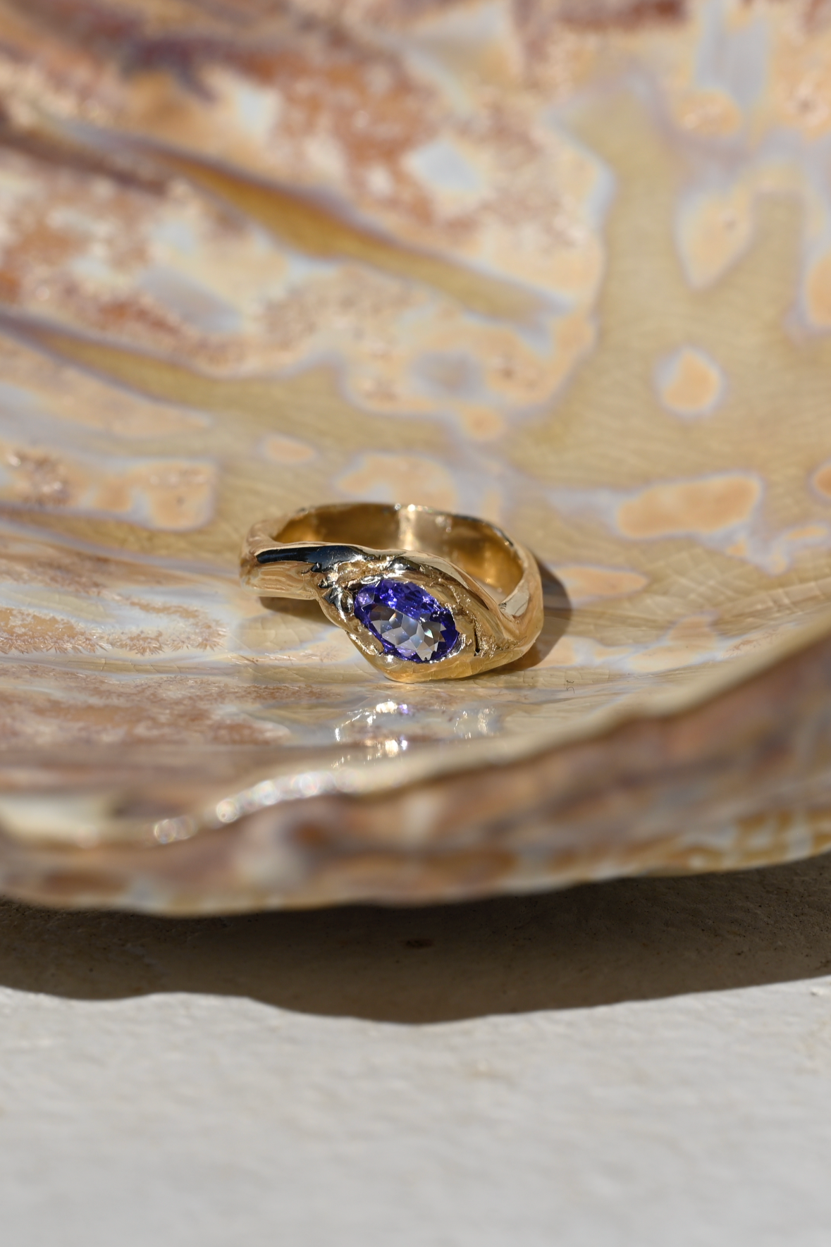 Gold ring with a blue gemstone on a shell