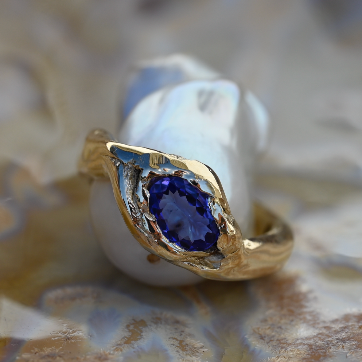 Gold ring with a blue gemstone on a textured surface