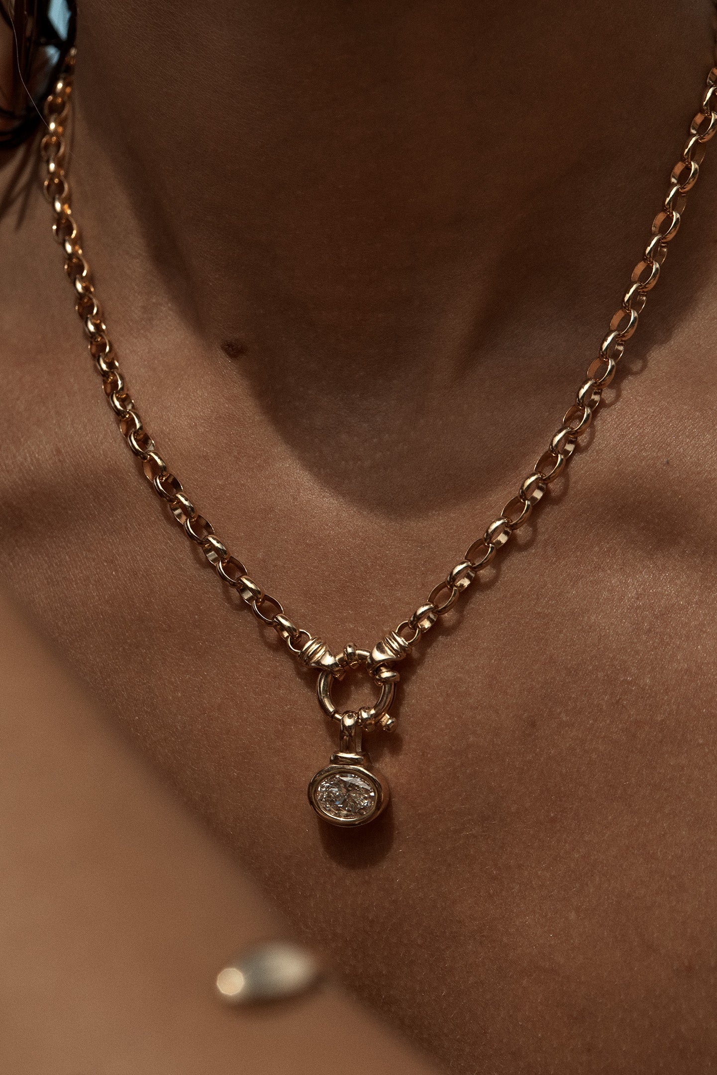 Gold chain necklace with a pendant on a person's neck